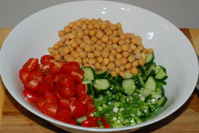 Chopped cucumber, green onion, tomatoes and chick peas ina salad bowl