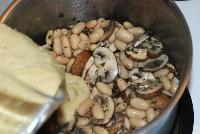 Adding the sauce to mushrooms herbs and beans