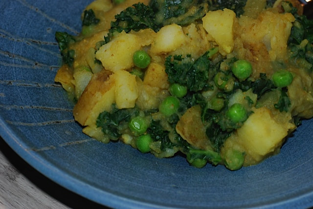 North Indian Potatoes and Greens served on a a blue plate--beansriceeverythingnice@weebly.com