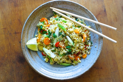 Thai Curry Tofu Fried rice pictured from above garnished with a wedge of lime and served with chop sticks