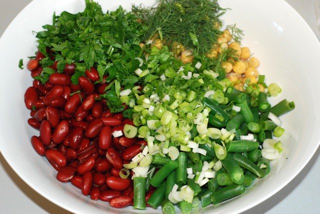 Chickpeas, kidney beans, green beans, parsley, dill, green onion in a bowl ready for dressing