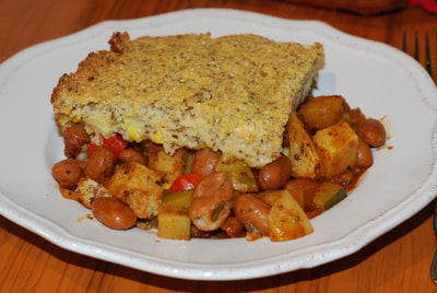 A slice of Quick Cornbread Casserole pictured from the side showing the top layer of cornbread with the seasoned bean and vegetable layer underneath