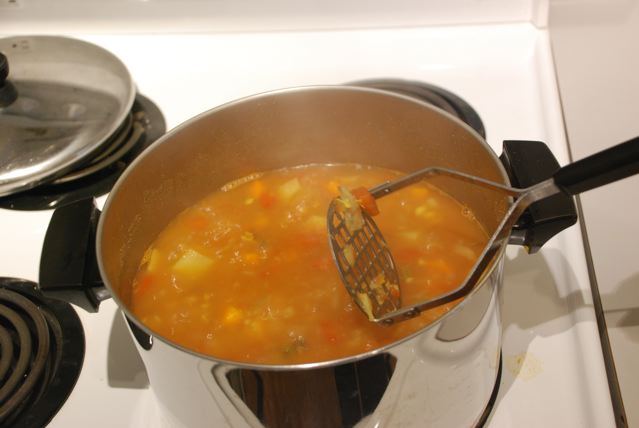 After simmering for 15 minutes, mash the soup with a potato masher 