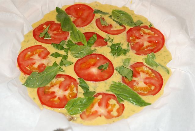 Tart topped with tomatoe slices and basil before cooking