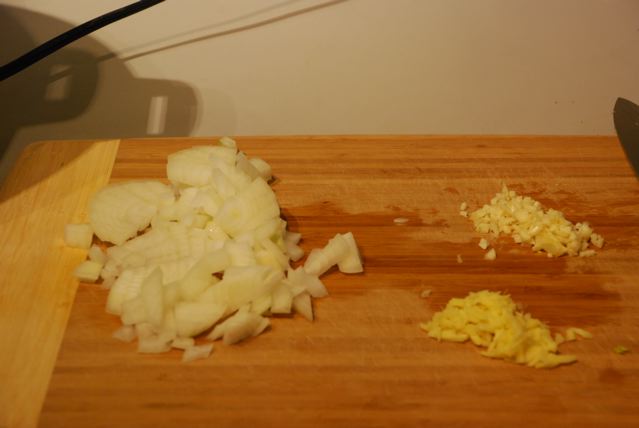 Chopped onion, garlic, and ginger on a cutting board