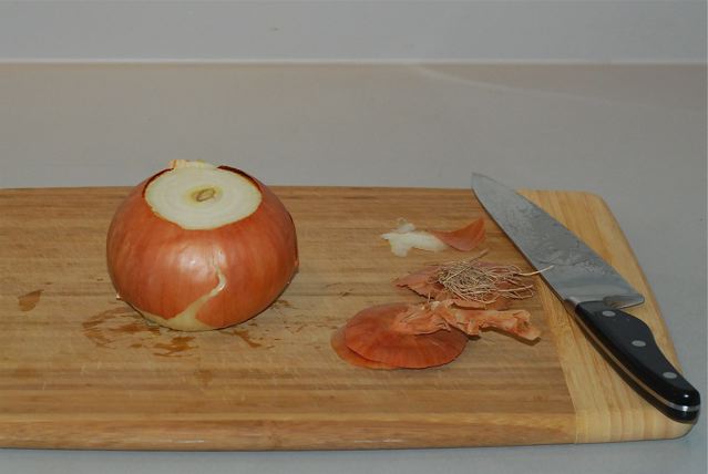 Onion on  a cutting board, stem and root ends removed 
