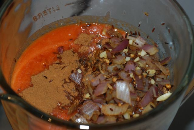 Add the cooked onion, garlic and toasted spices to the blender with the tomatoes