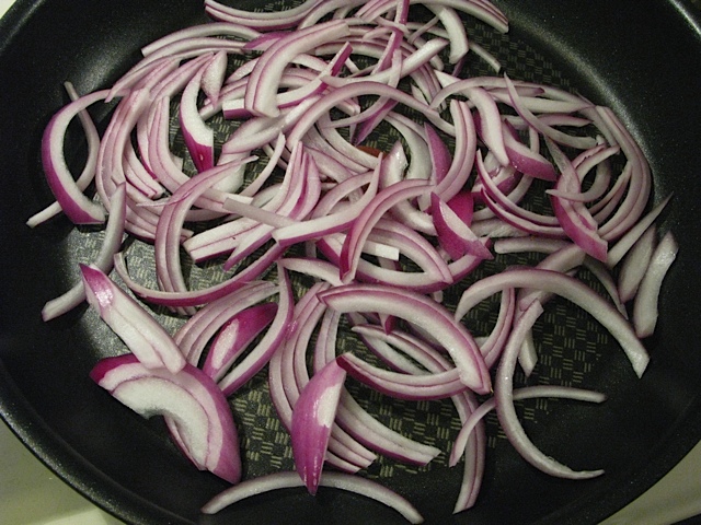 Sliced red onion in a non-stick pan