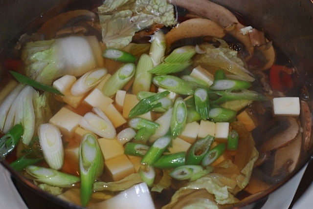 Add the napa cabbage, tofu, and green onion to the stock