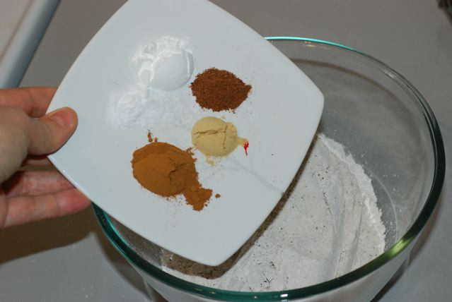 Cinnamon, ginger, nutmeg, baking powder, baking soda being added to the flour