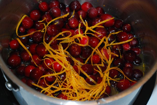 Cranberries, orange zest and juice, and maple syrup in a pot